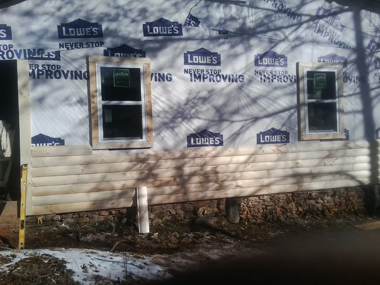 House wrap and new log siding going up on an exterior wall in Ethel