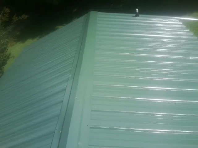 New green metal panels meeting at the ridge of a roof — Flat Roof Repair work by our crew in Ethel