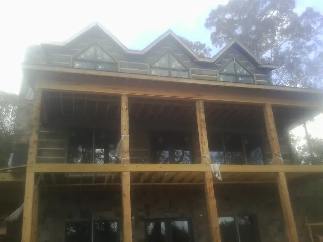 Dormers and porch framing on a large log home under construction — Roof Coating work by our crew in Ethel