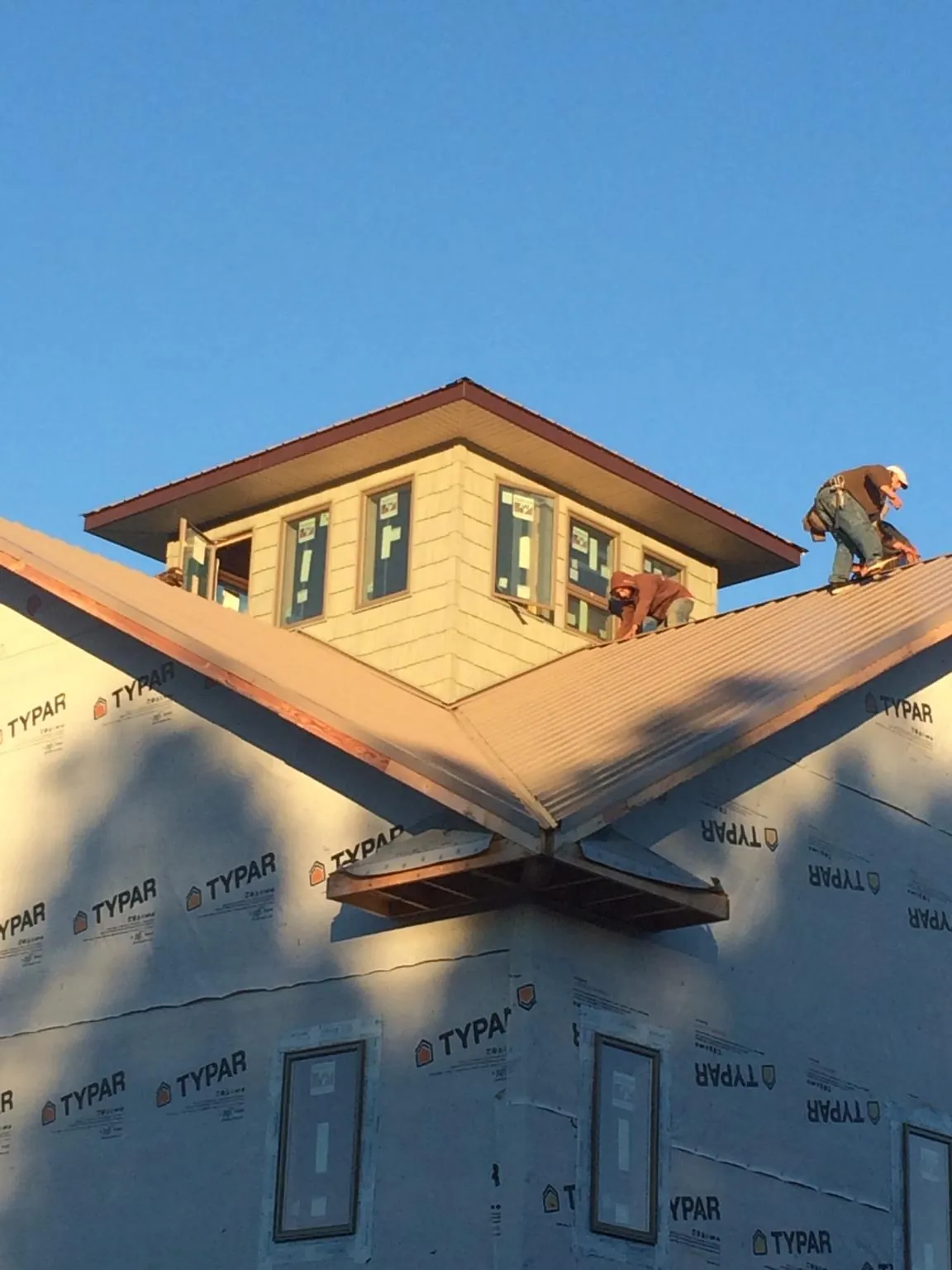 Roofers working around a rooftop cupola on a new metal roof at sunset — Roof Waterproofing in Ethel by Roofing Brothers